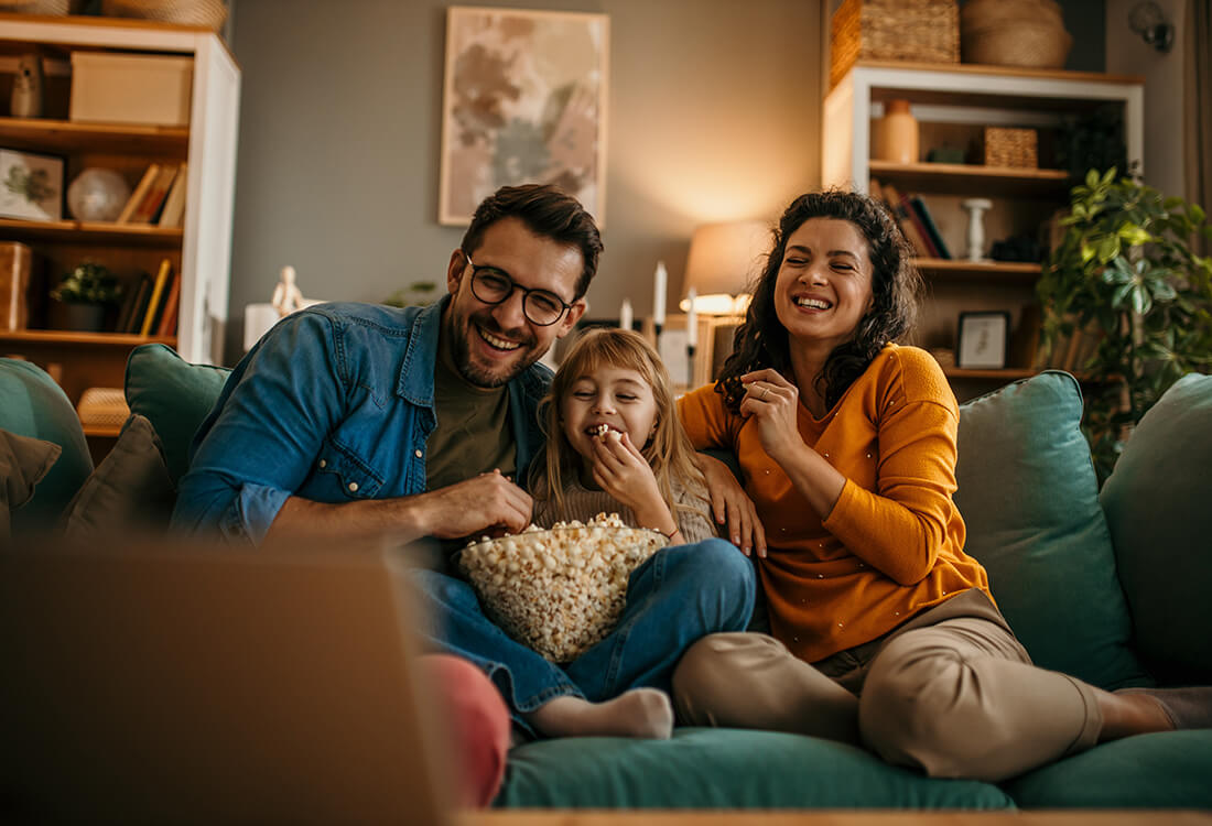 family on couch eating popcorn and laughing